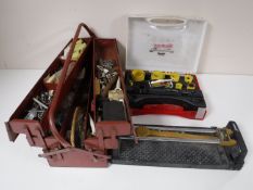 A tile cutter together with a metal concertina tool box and one other case