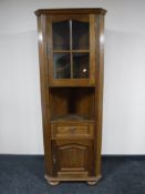 An oak corner glazed cabinet