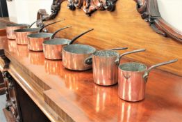 A good set of seven Victorian graduated copper pans with cast iron handles,
