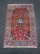 A Kashan rug, a central strawberry medallion enclosed by blue scrolling vine borders, 148cm by 98cm.