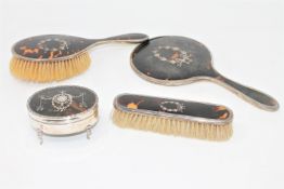 A four piece silver and tortoiseshell dressing table set including a trinket box on cabriole legs.