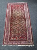 A Tekke design rug, on mauve ground, 207cm by 107cm.