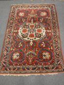A Bakhtiari rug, West Persia, with a large central medallion upon a strawberry field,