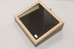 A glazed and gilt, sloped-front jewellery display box, width 47cm.