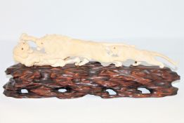 A Japanese carved ivory group of three fighting lions, Meiji period, on carved naturalistic base,