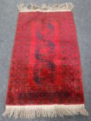 A fringed Afghan Bokhara rug, on red ground, 178cm by 101cm.