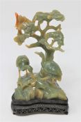 A Chinese jade carving of two cranes beneath a tree, on carved hardwood base, height 21cm.