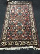 A Saroukh rug, the central field of serrated leafy vines upon a salmon ground, 233cm by 128cm.