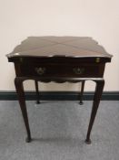 A late Victorian mahogany envelope games table and contents, width 56cm.