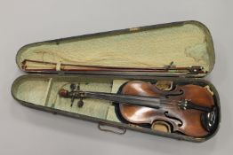 A late nineteenth century violin with carved neck, and two later bows, back length 14 inches.