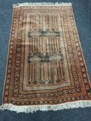 A fringed Persian village rug, on rust ground, 200cm by 125cm.