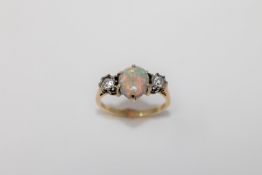 An 18ct gold opal and diamond ring, an oval cabochon opal flanked by two old cut diamonds,