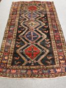 A Persian Lori long rug, with five central medallions upon a black field, 280cm by 160cm.