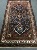 A Persian rug, with a central blue medallion of stylized flowers, enclosed by cream borders,