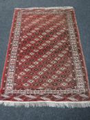 A fringed Afghan rug on red ground, of geometric design, 200cm by 135cm.