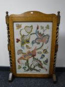 An Edwardian oak fire screen with embroidered panel, width 64cm.