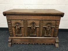 A heavily carved oak blanket chest, with carved detail depicting religious figures, with key,