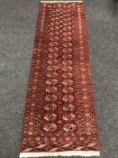 A Tekke runner, on red ground, 240cm by 77cm.