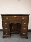 A George III oak kneehole desk, fitted seven drawers around a cupboard, on bracket feet, width 87cm.