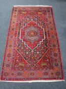 A Persian rug, with a central stepped medallion upon a midnight blue field of serrated leaves,