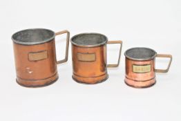 A set of three graduated copper grain measures, the tallest 11cm.