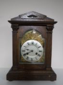An early twentieth century oak cased mantel clock with brass and silvered dial