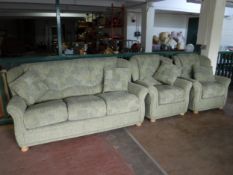 A three piece lounge suite upholstered in green fabric on bun feet and scatter cushions