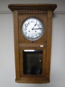 An early twentieth century oak cased wall clock with silvered dial