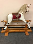 A painted wooden rocking horse on pine stand