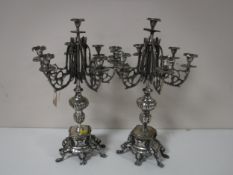 A pair of white metal candelabrum on stands