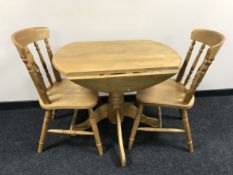 A contemporary pine effect drop leaf kitchen table together with two chairs