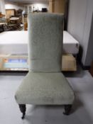 An antique bedroom chair upholstered in green floral fabric on turned legs