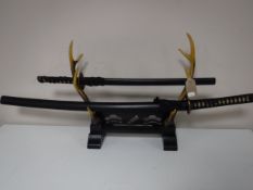 Two reproduction samurai swords on antler stand