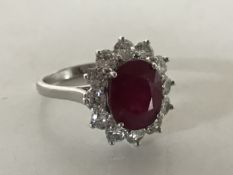 An 18ct white gold ruby and diamond cluster ring, size L.