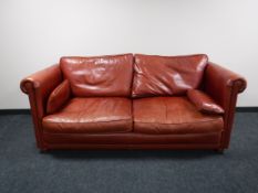 A contemporary red leather scroll armed settee