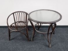 A circular bamboo and wicker glass topped table and an armchair