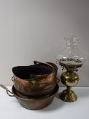 An antique copper twin handled pan together with a copper coal bucket and a brass oil lamp with