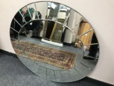 An all glass oval mirror, 92 cm x 107 cm.