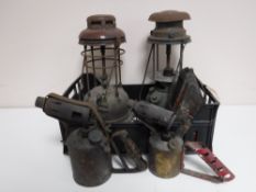 A basket of three vintage oil lamps and two blow torches