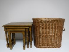 A nest of three oak tables and a wicker laundry basket