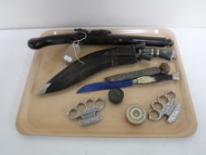 A tray of weapons including a flintlock pistol, Khukri knife in sheath, tin of starter pistol caps,