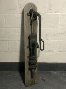 A cast iron water pump mounted on a board