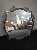 An ornate brass framed bevelled edge mirror