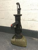 A cast iron water pump mounted on stone base