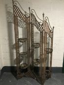 A wrought iron three way folding garden screen with planters