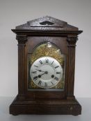 An early twentieth century oak cased mantel clock with brass and silvered dial
