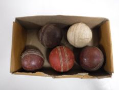A box containing five vintage cricket balls