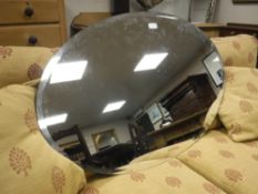 A frameless oval mirror,