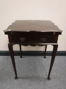 A late Victorian mahogany envelope games table and contents, width 56cm.