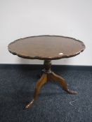 A walnut tilt top pie crust edge occasional table on a tripod base